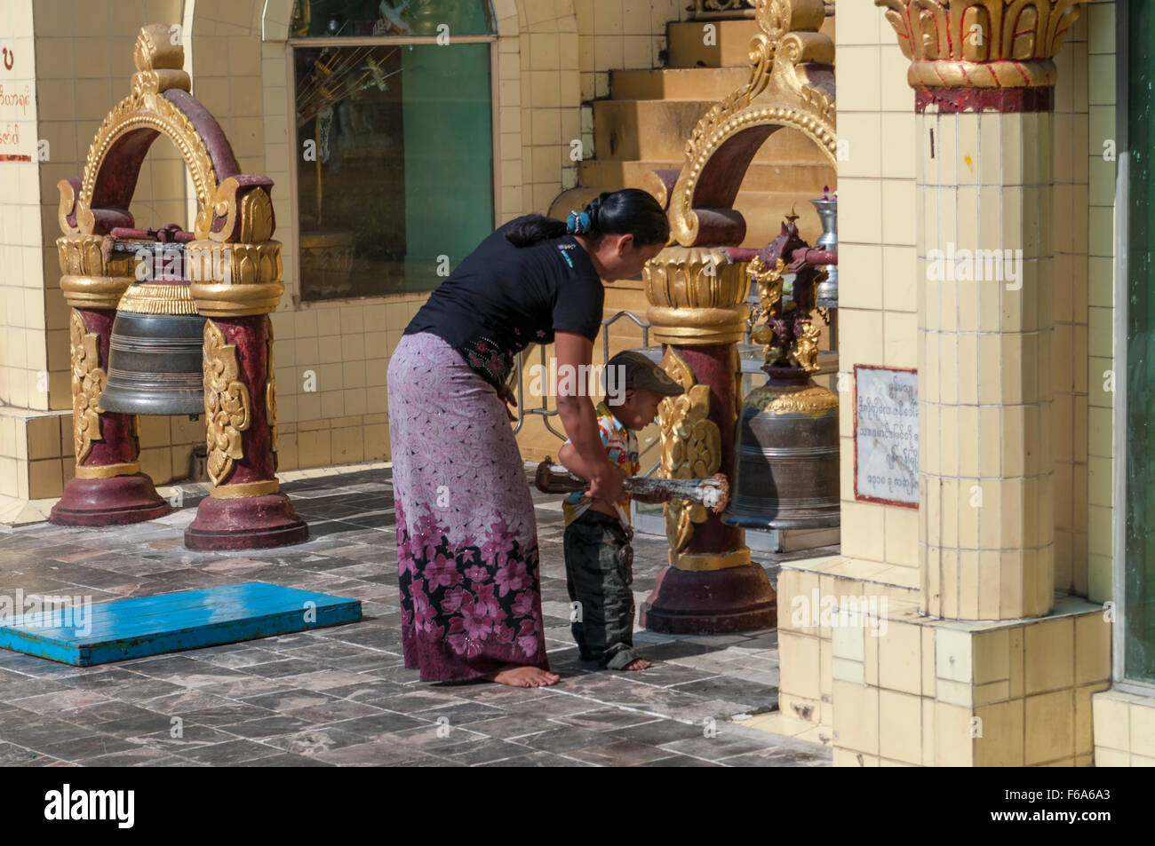 Mutter mit Kind Läuten einer Glocke an die Sule-Pagode in Yangon (Rangoon), Myanmar. Stockfoto