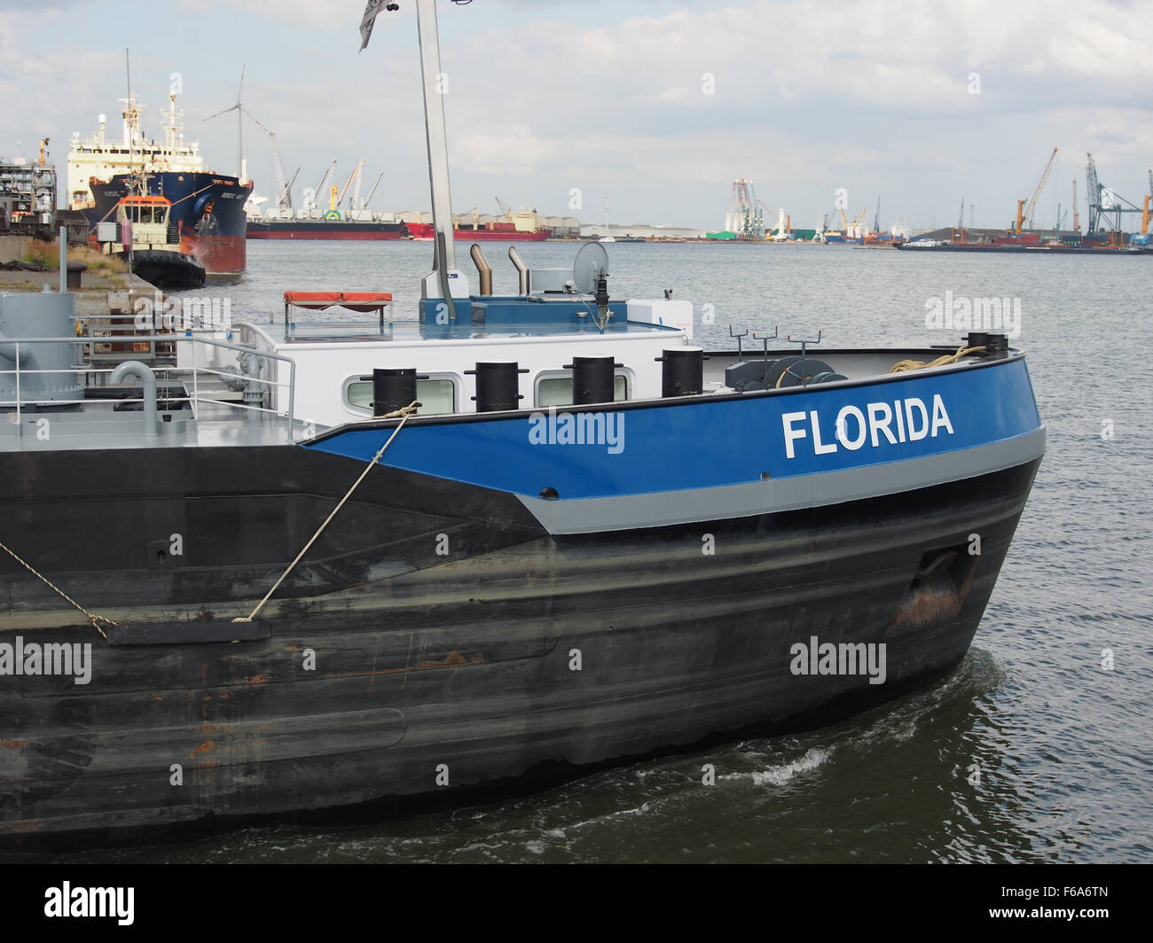 Das Bild zeigt ein großes Containerschiff und Öltanker in Boudewijnsluis in Florida, das neben Kränen zum Entladen von Fracht angedockt ist. Das Schiff transportiert eine Mischung aus allgemeinen Gütern, einschließlich Kohle, Getreide und Gas. Diese Szene spiegelt die Logistik und den Seeverkehr an einem stark frequentierten Dock wider und hebt die wichtigsten Infrastrukturen im weltweiten Seeverkehr und Handel hervor. Stockfoto