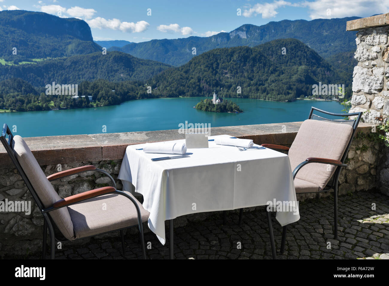 Tabelle mit Emty Platte im Freien serviert. Blick über den See Bled, Insel mit Kirche und Alpen im Hintergrund. Slowenien. Stockfoto