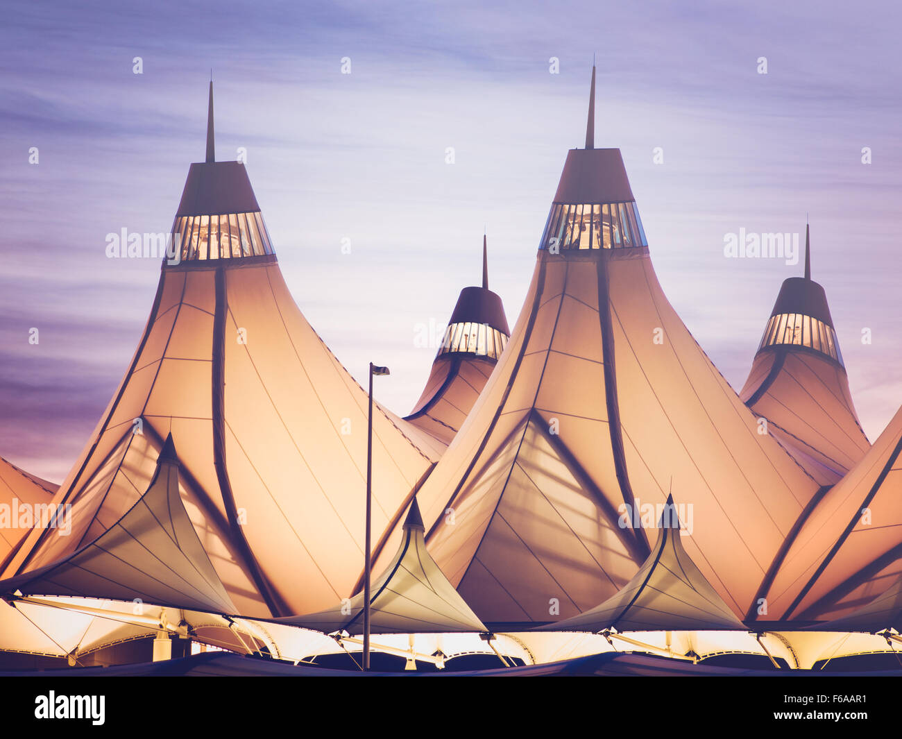 Glühende Zelte von DIA bei Sonnenaufgang. Denver International Airport bekannt für Spitzen Dach. Gestaltung von Dach reflektiert Schnee-capp Stockfoto