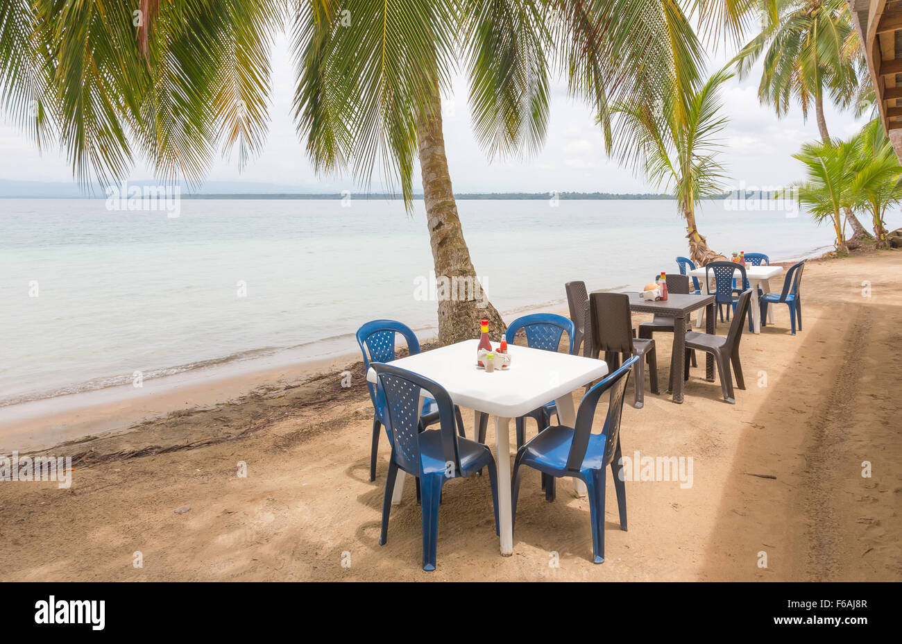 Restauranttische unter den Palmen am Strand Stockfoto
