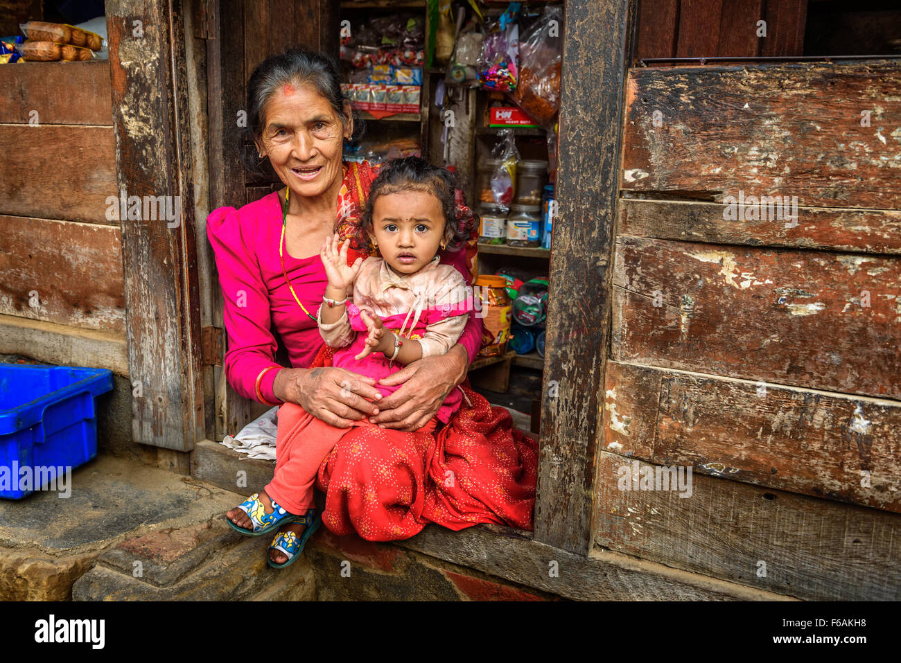 Waren in ihrem Laden verkauft alte nepalesische Frau mit einem Kind. Stockfoto