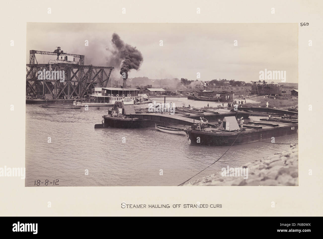 Dieses Bild zeigt einen Dampfer, der von einer gesträngten Bordsteinkante gezogen wird und die technischen Herausforderungen des Brückenbaus und der Eisenbahninfrastruktur hervorhebt. Stockfoto