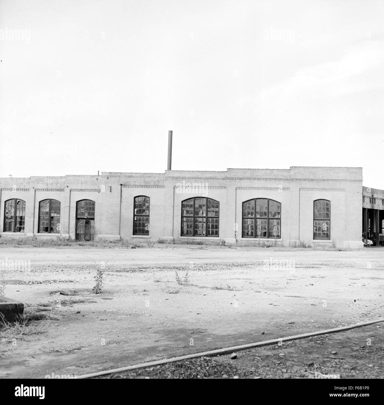 Dieses Bild zeigt das Southern Pacific Roundhouse in Austin, Texas, eine wichtige Einrichtung für die Wartung und Wartung von Lokomotiven für die Southern Pacific Railroad. Das Rundhaus, ein kreisförmiges Gebäude mit Gleisen, war ein wesentlicher Bestandteil des Bahnbetriebs. Sie ermöglichte ein effizientes Management von Zügen, Reparaturen und Lagern und spielte eine entscheidende Rolle bei der Expansion des Eisenbahnverkehrs in den USA Stockfoto