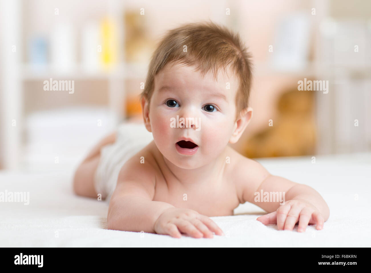 Lustige kleine Baby auf dem Bauch liegend und lächelnd Stockfoto