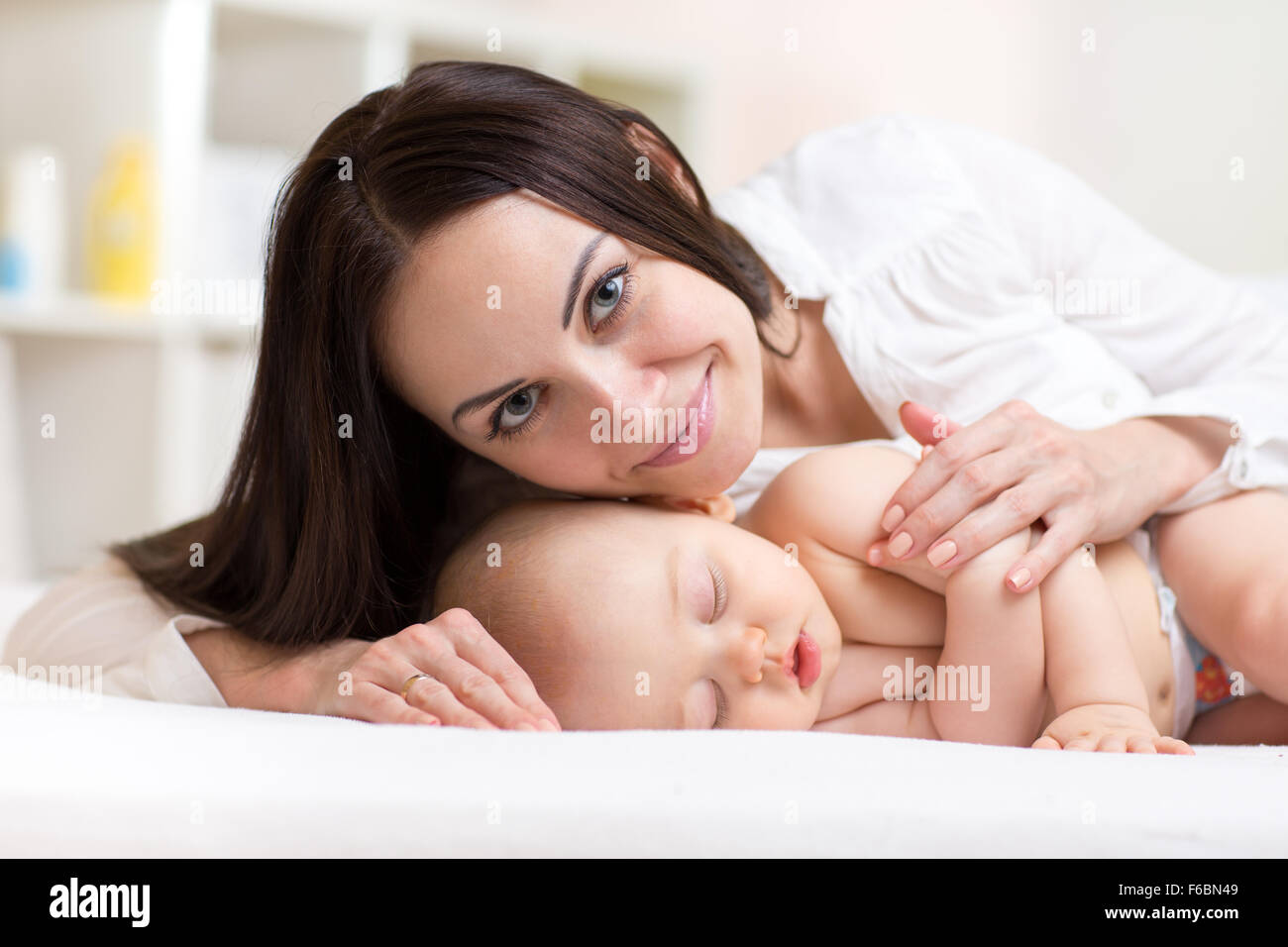 Junge Mutter mit schlafenden Baby im Bett Stockfoto