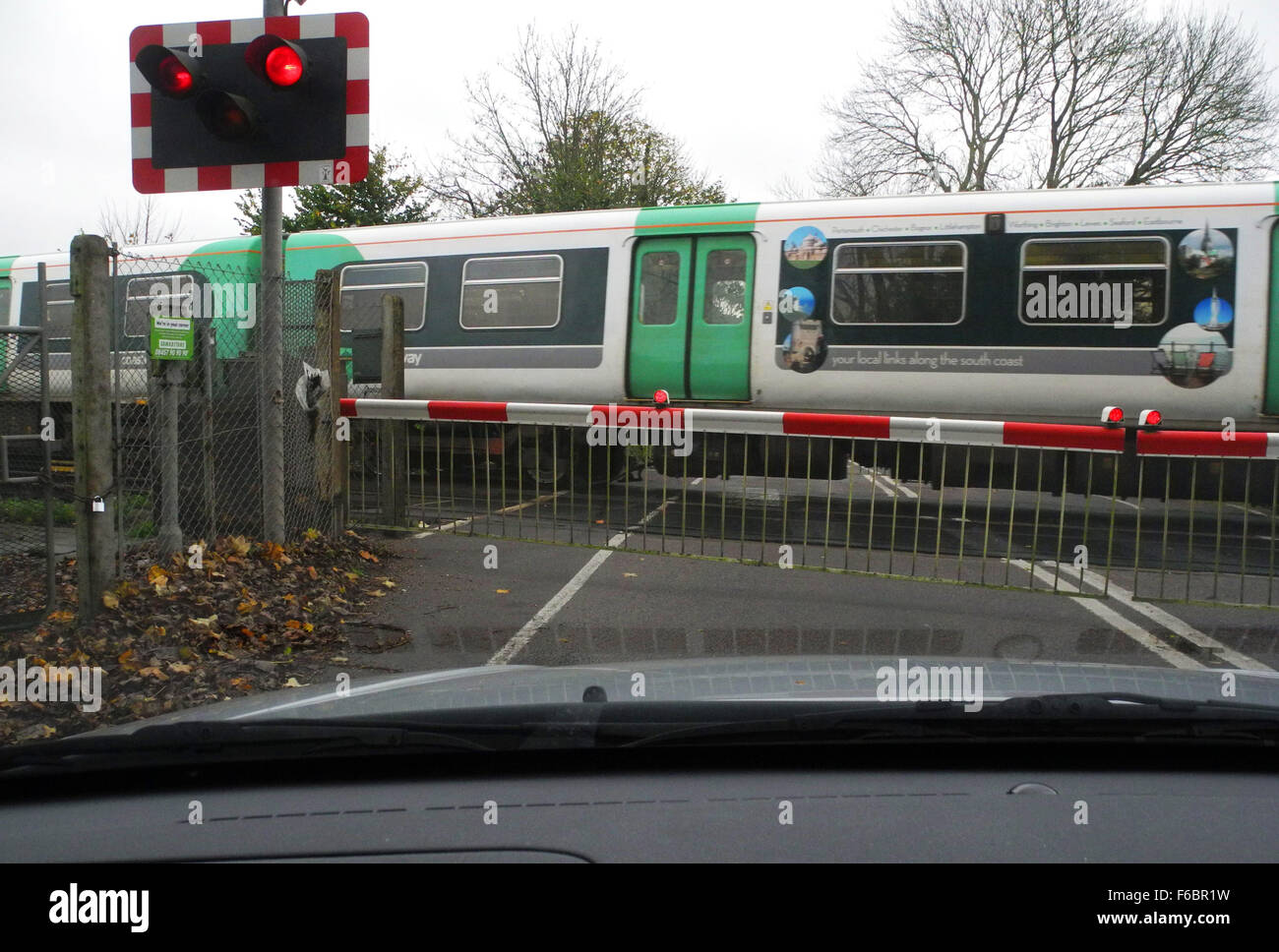 Bahnübergang mit Tore geschlossen und Zug überqueren. Dieses ist in West Drayton in der Nähe von Chichester in West Sussex UK Stockfoto