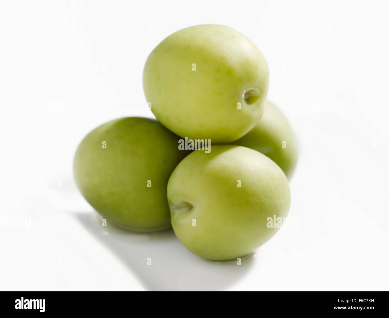 Vier grüne Oliven auf einem weißen Teller gestapelt Stockfoto