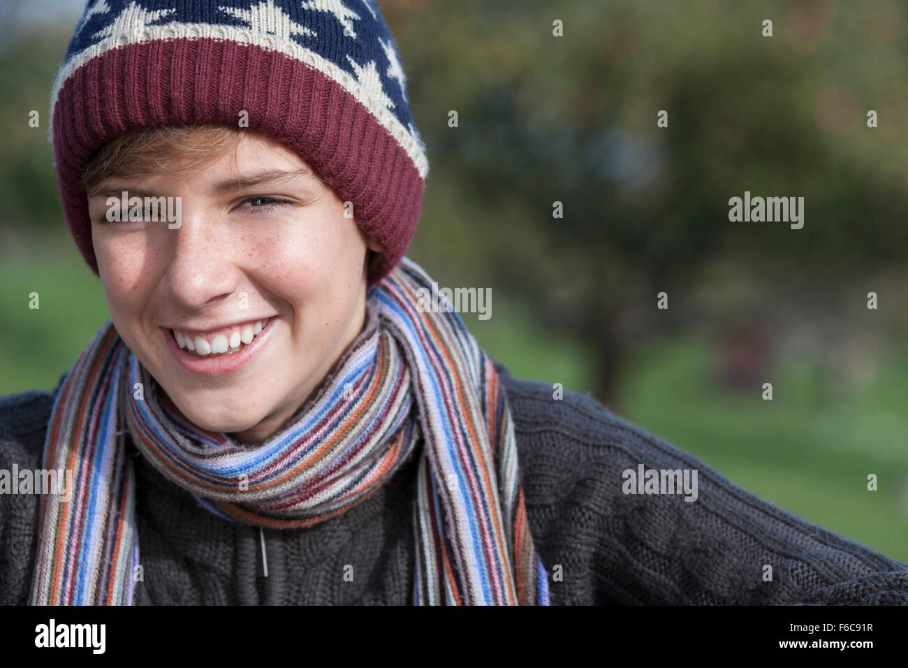 Glücklich lachende männliche junge blonde Teenager Kind außerhalb in in warme Kleidung wollene Mütze und Schal Stockfoto