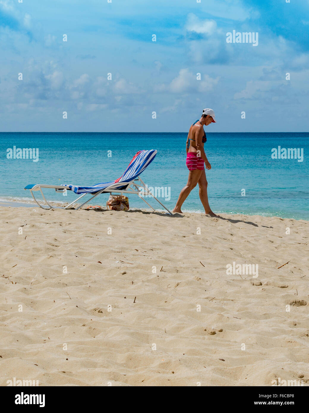 Eine Kaukasische Frau in ihren 40ern geht auf das Wasser zum Abkühlen nach dem Sonnen am Strand von St. Croix, Amerikanische Jungferninseln. Stockfoto