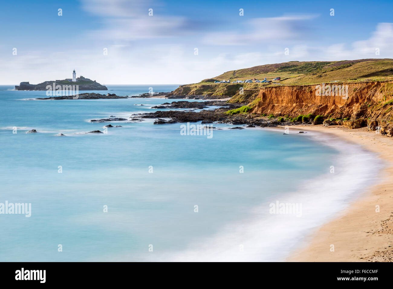 Wellen über die Felsen bei Godrevy Point, Blick auf den Leuchtturm auf der Insel Godrevy, Cornwall, England Stockfoto