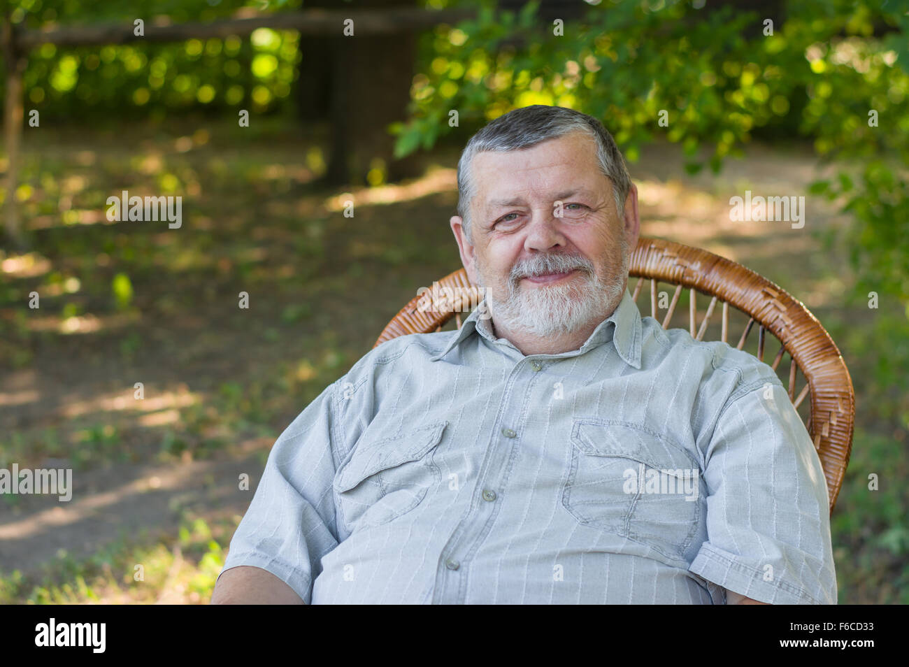 Outdoor Portrait von senior glücklich sitzt auf einem Stuhl im Sommerpark Stockfoto