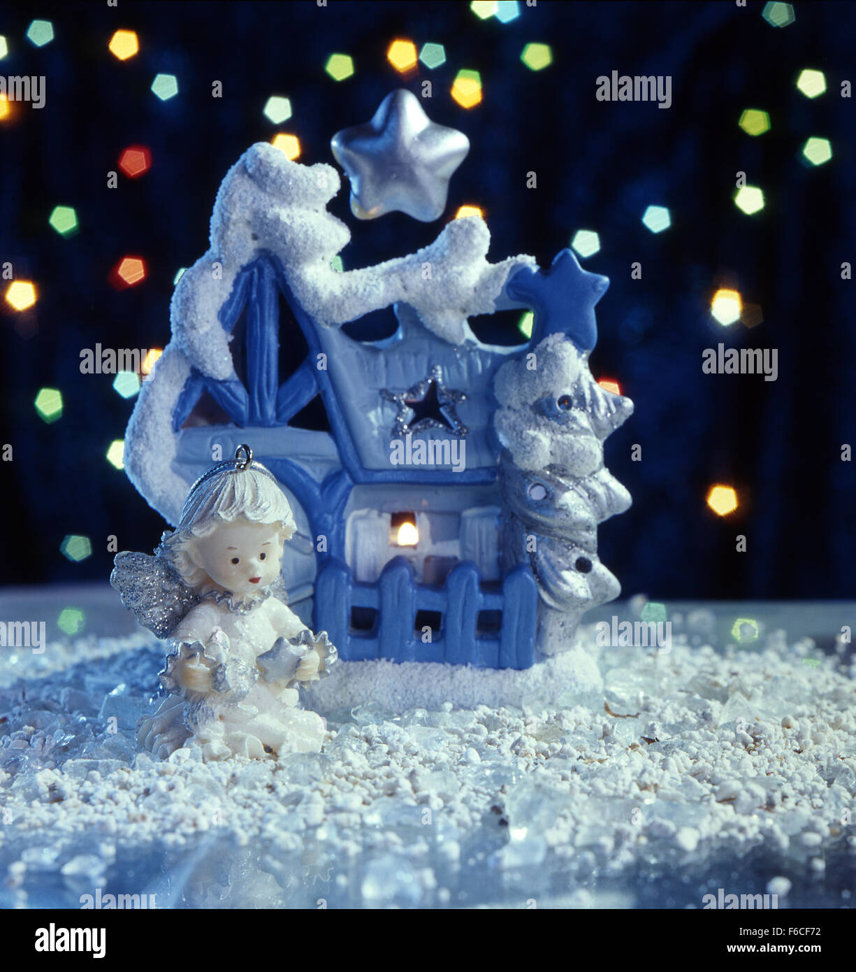Festliches Silvester, Weihnachten Stilleben ein fantastisches Spielzeug-Lodge und ein Spielzeug-Engel mit einem Stern in der Nacht auf Schnee. schwarzer Hintergrund, Stockfoto