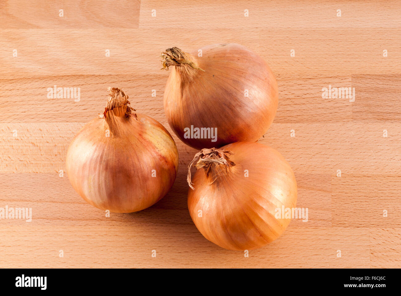 Drei weiße Zwiebeln auf einem Holzbrett Hintergrund. Stockfoto