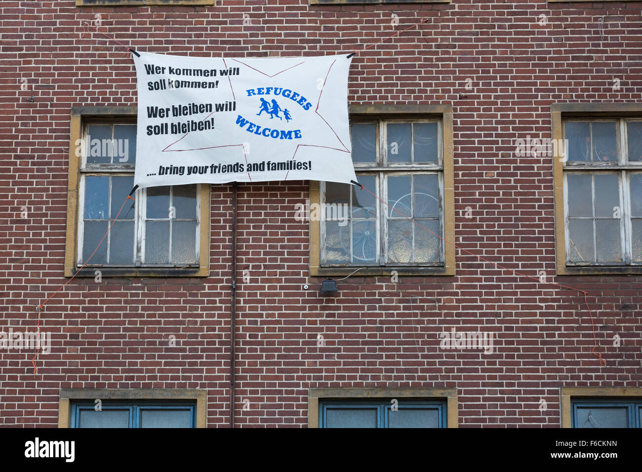 Ein Banner außerhalb eines Gebäudes sagt Flüchtlinge willkommen. Wer kommen will, sollte kommen. Wer bleiben will sollte bleiben. Stockfoto