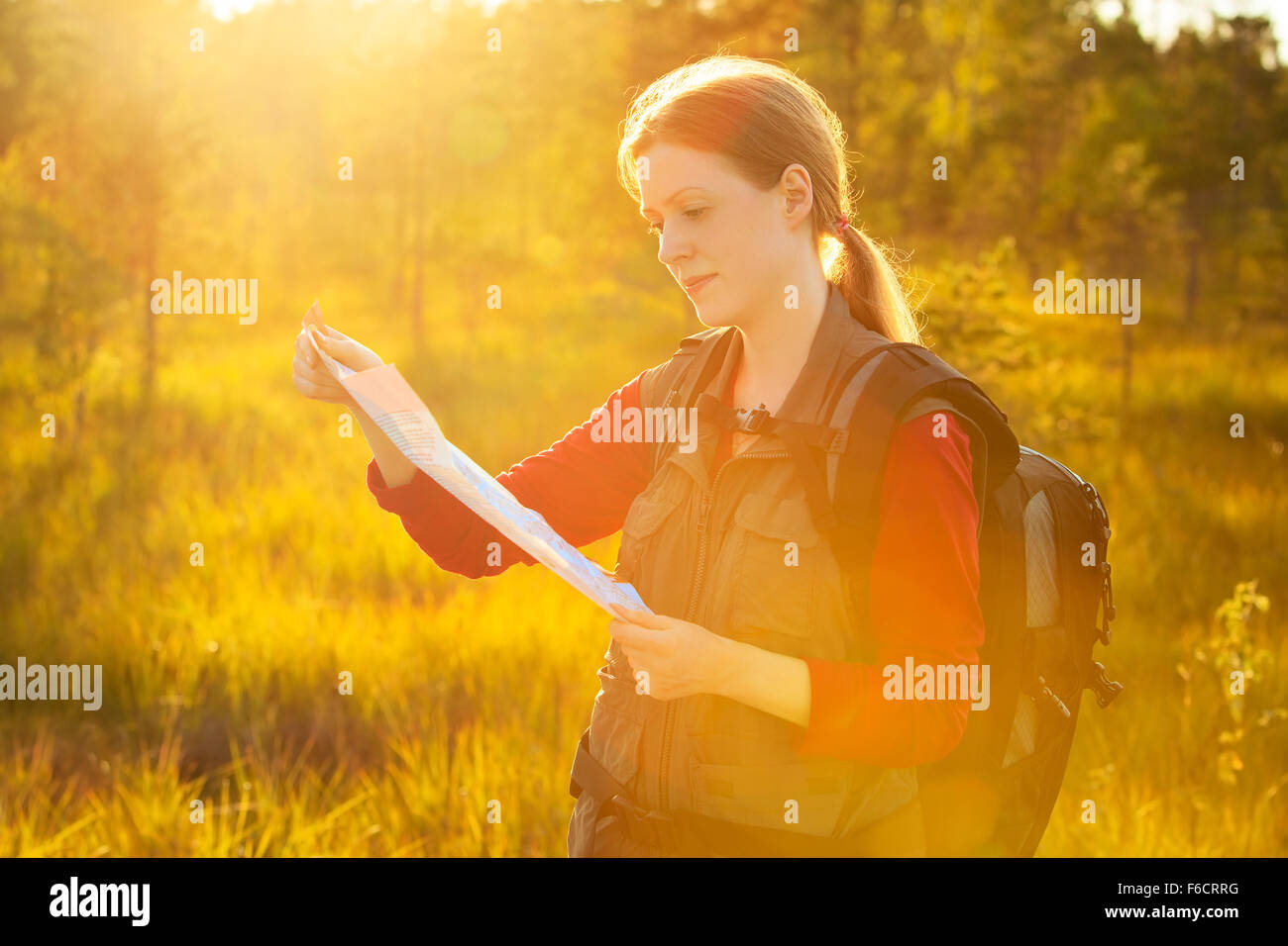 Junge Frau touristische Karte Porträt. Leuchtend rote Abendlicht. Stockfoto