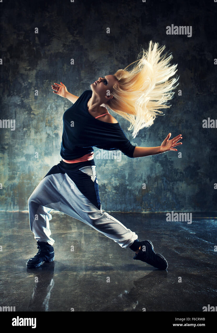 Moderne junge Frau Tänzerin. Auf dunklen Stein Wand Hintergrund. Stockfoto