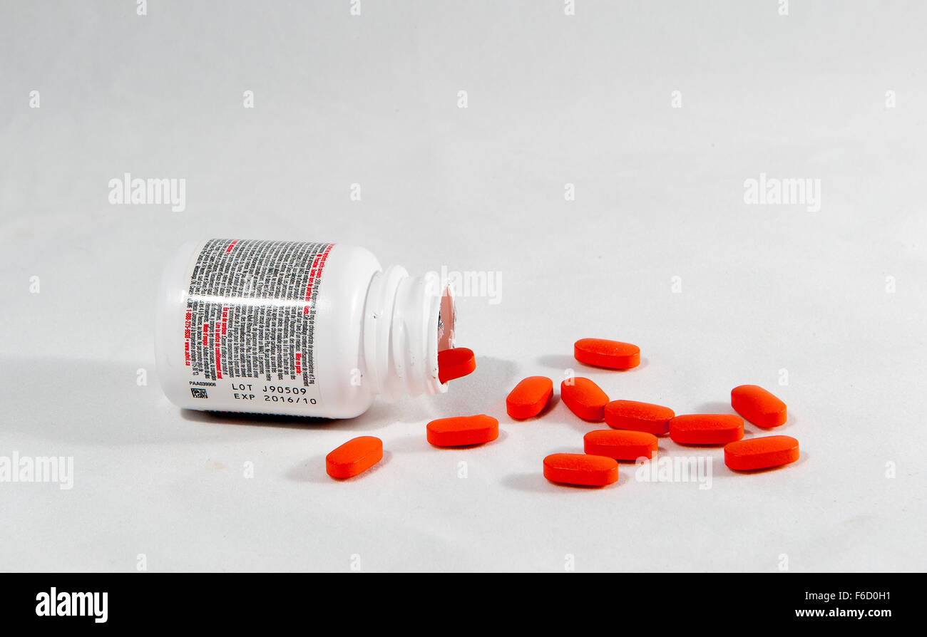 Ein Container von Advil auf seiner Seite und verschüttete Tabletten vor einem weißen Hintergrund Stockfoto