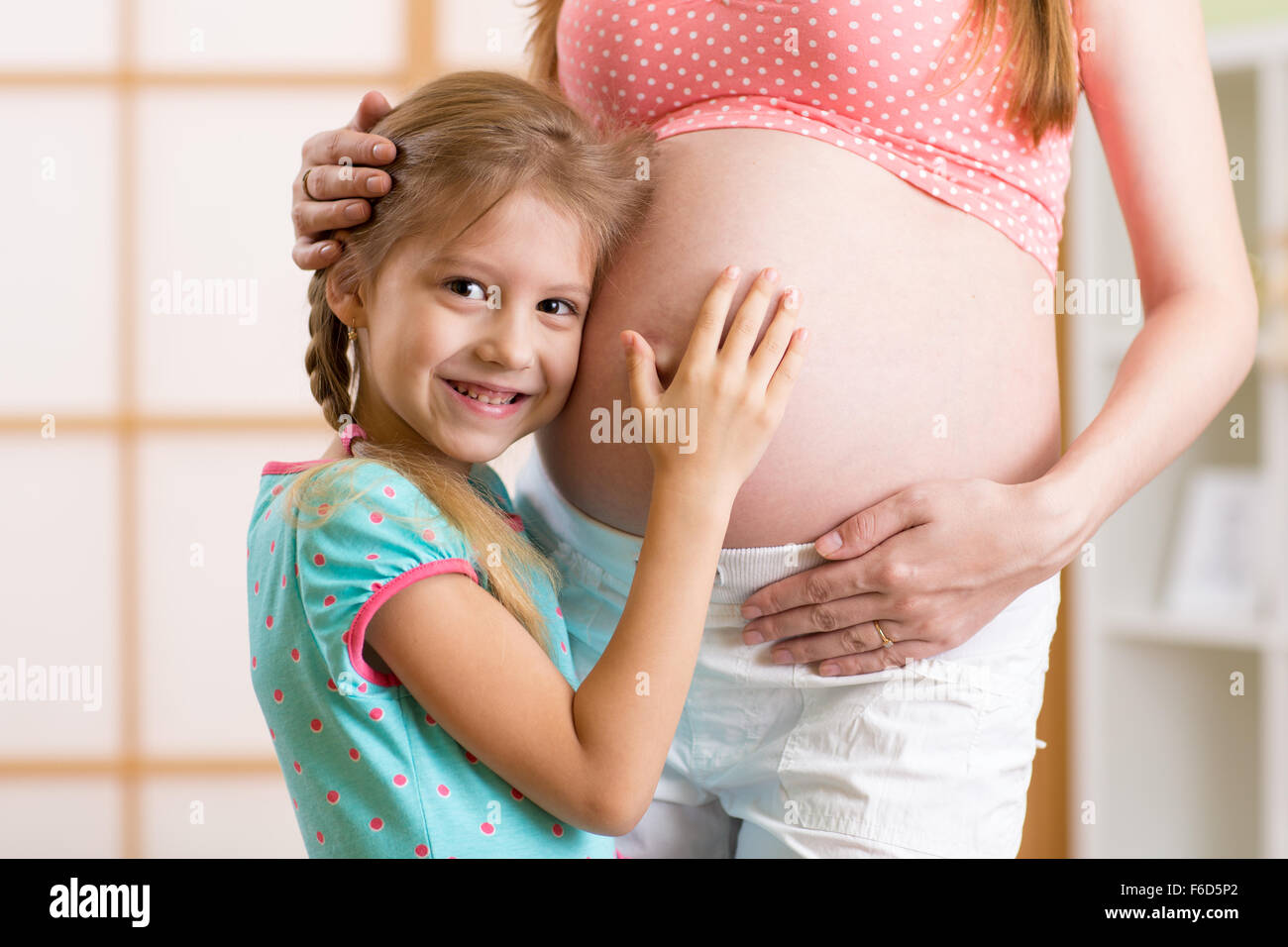 glückliches Kind umarmt schwangere Mutter Bauch Stockfoto