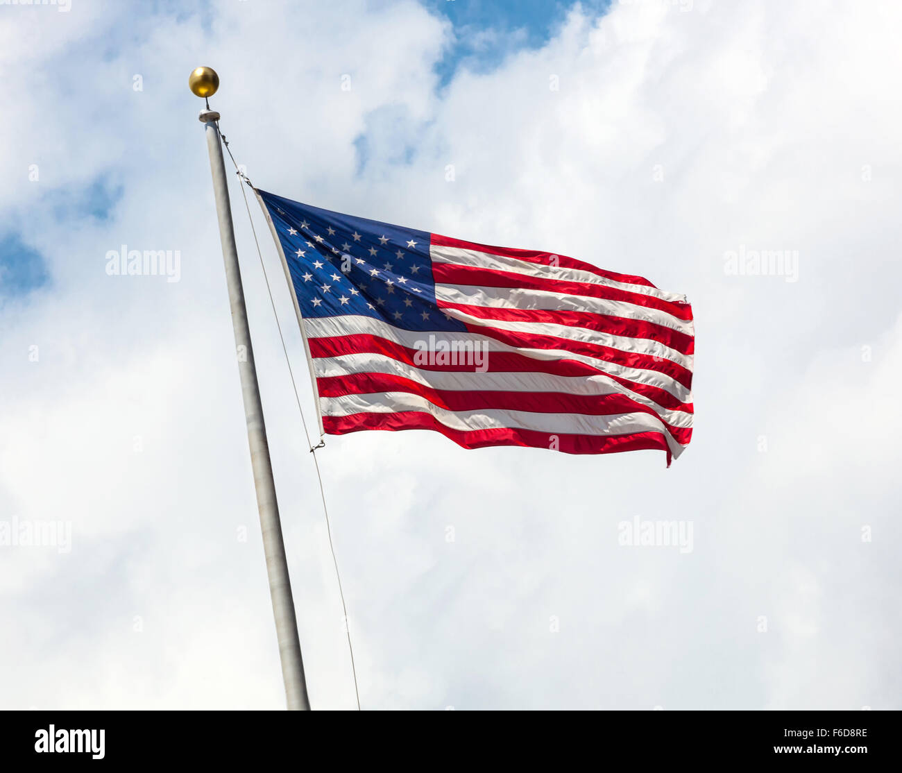 USA-Flagge leuchtet hell an einem windigen Tag gegen Wolken. Stockfoto