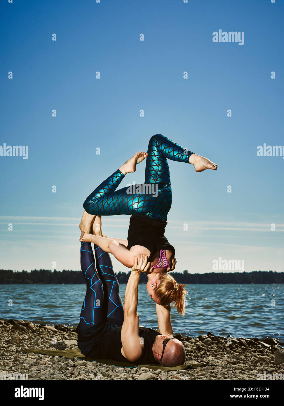 Sportliches Paar Training Acro Yoga im Freien, Sommer, Meer und blauer Himmel Stockfoto