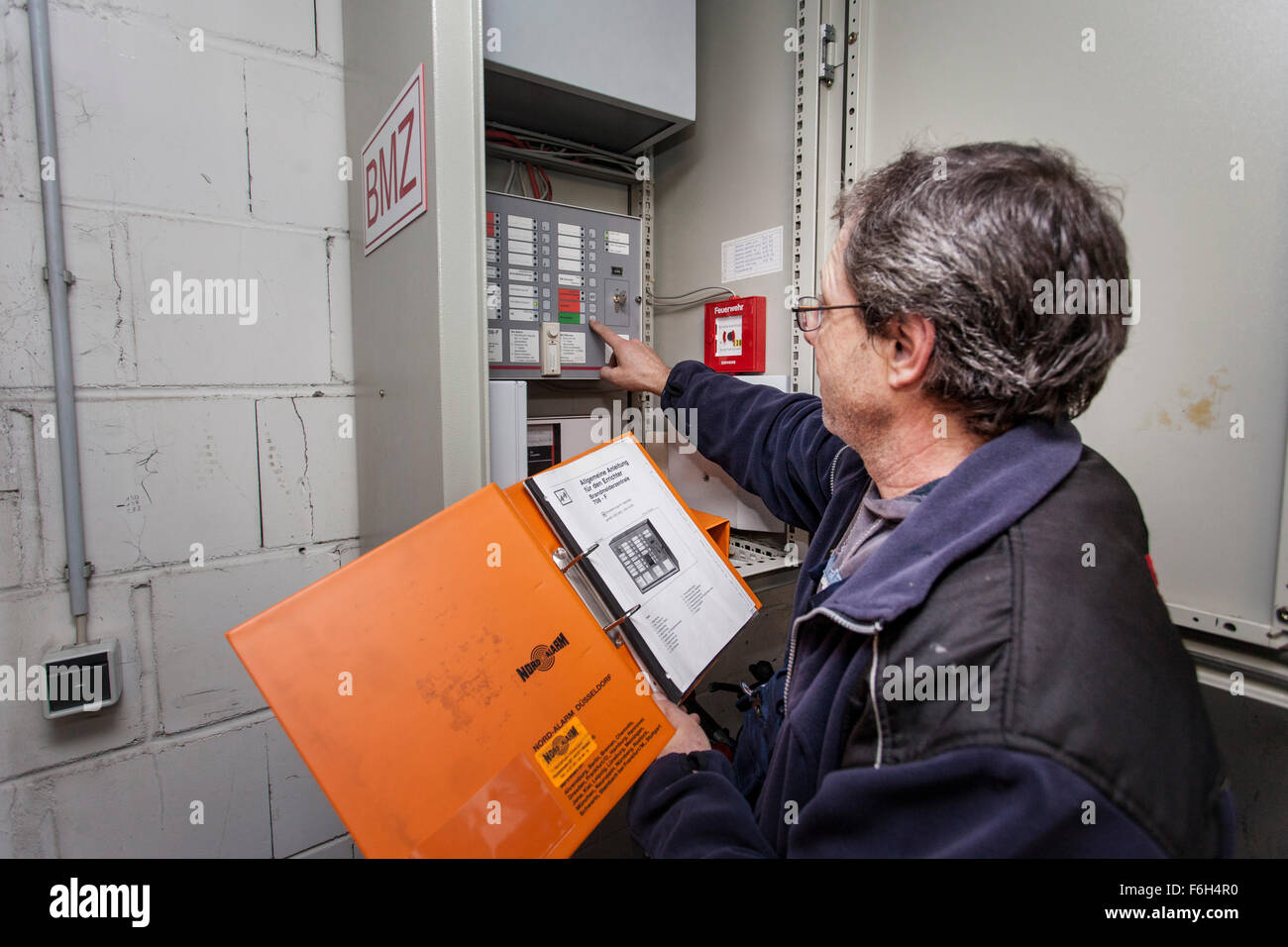 Hausmeister prüft eine Brandmeldezentrale in Wohngebäude. Stockfoto