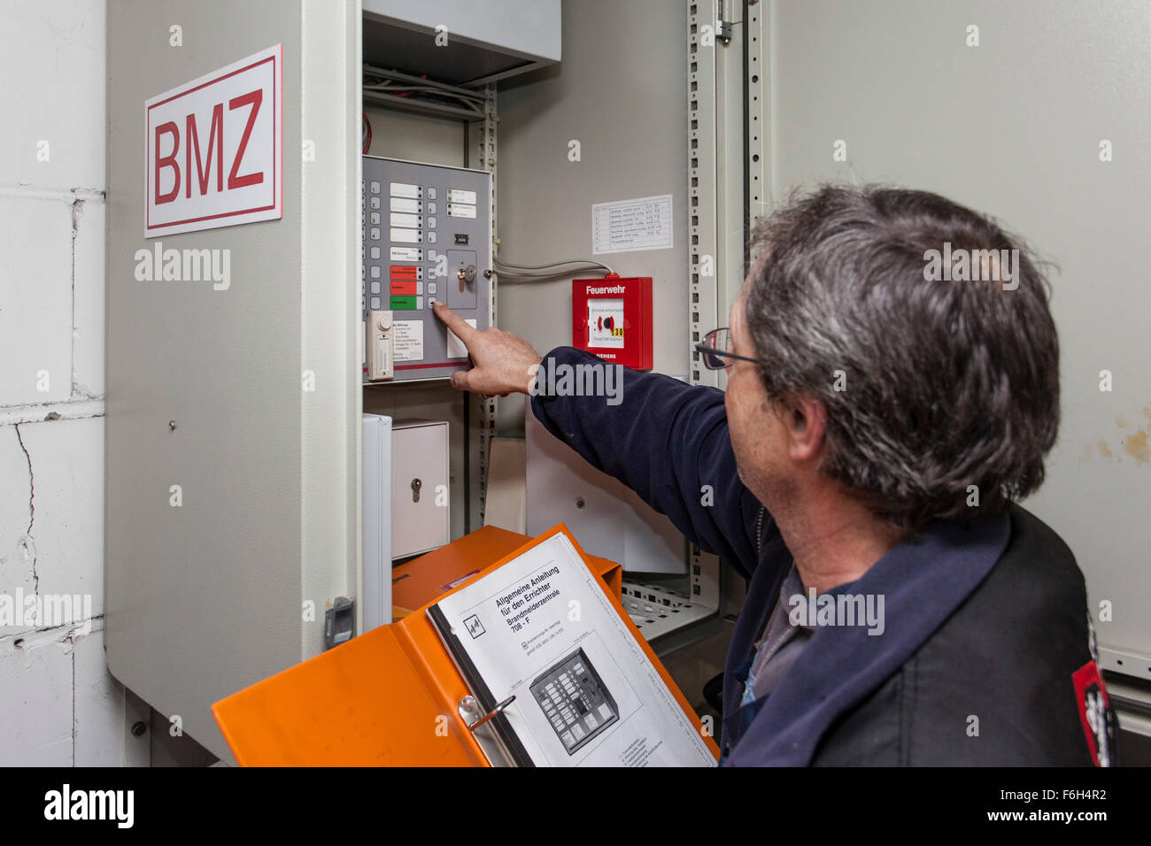 Hausmeister prüft eine Brandmeldezentrale in Wohngebäude. Stockfoto