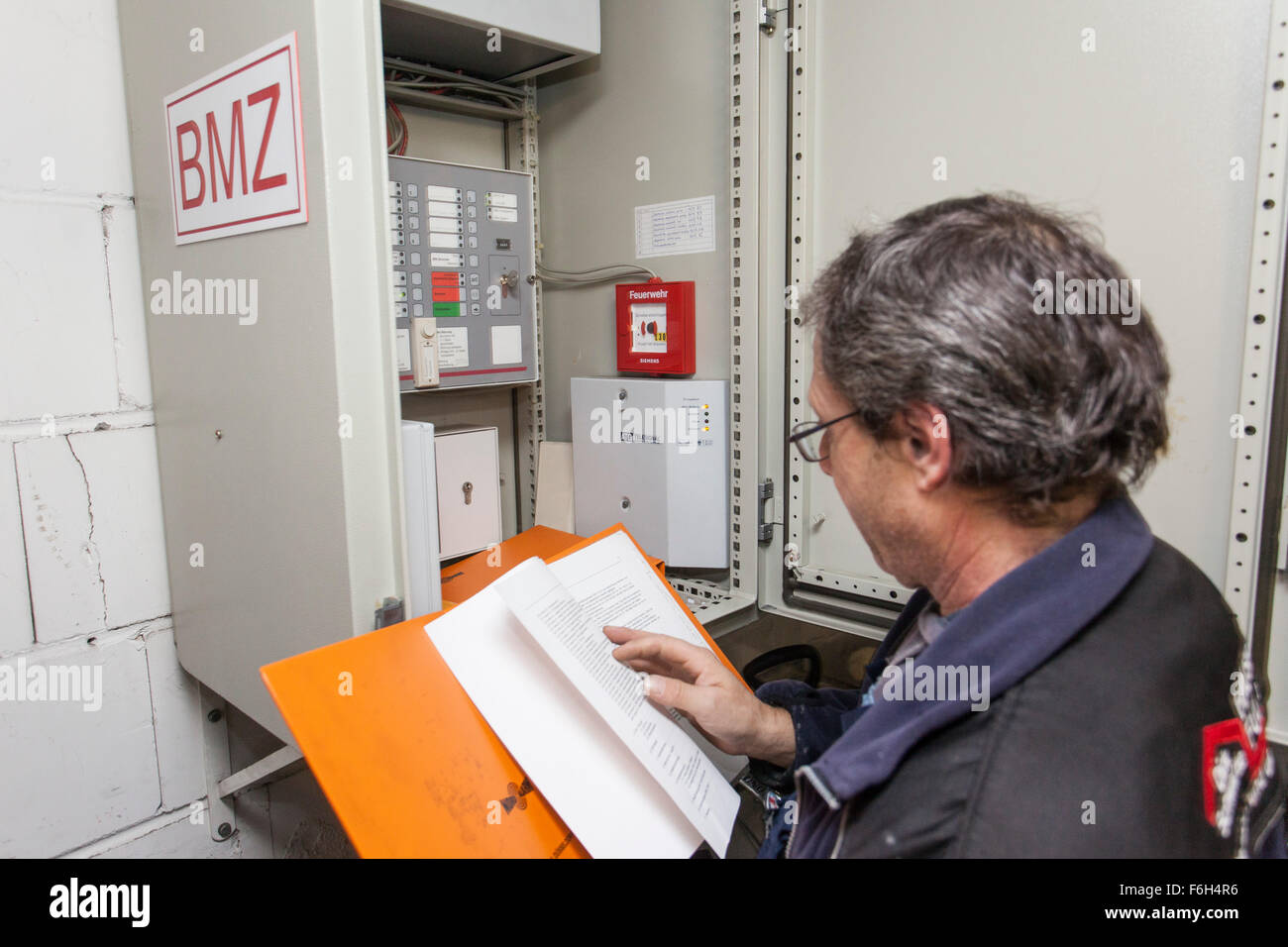 Hausmeister prüft eine Brandmeldezentrale in Wohngebäude. Stockfoto