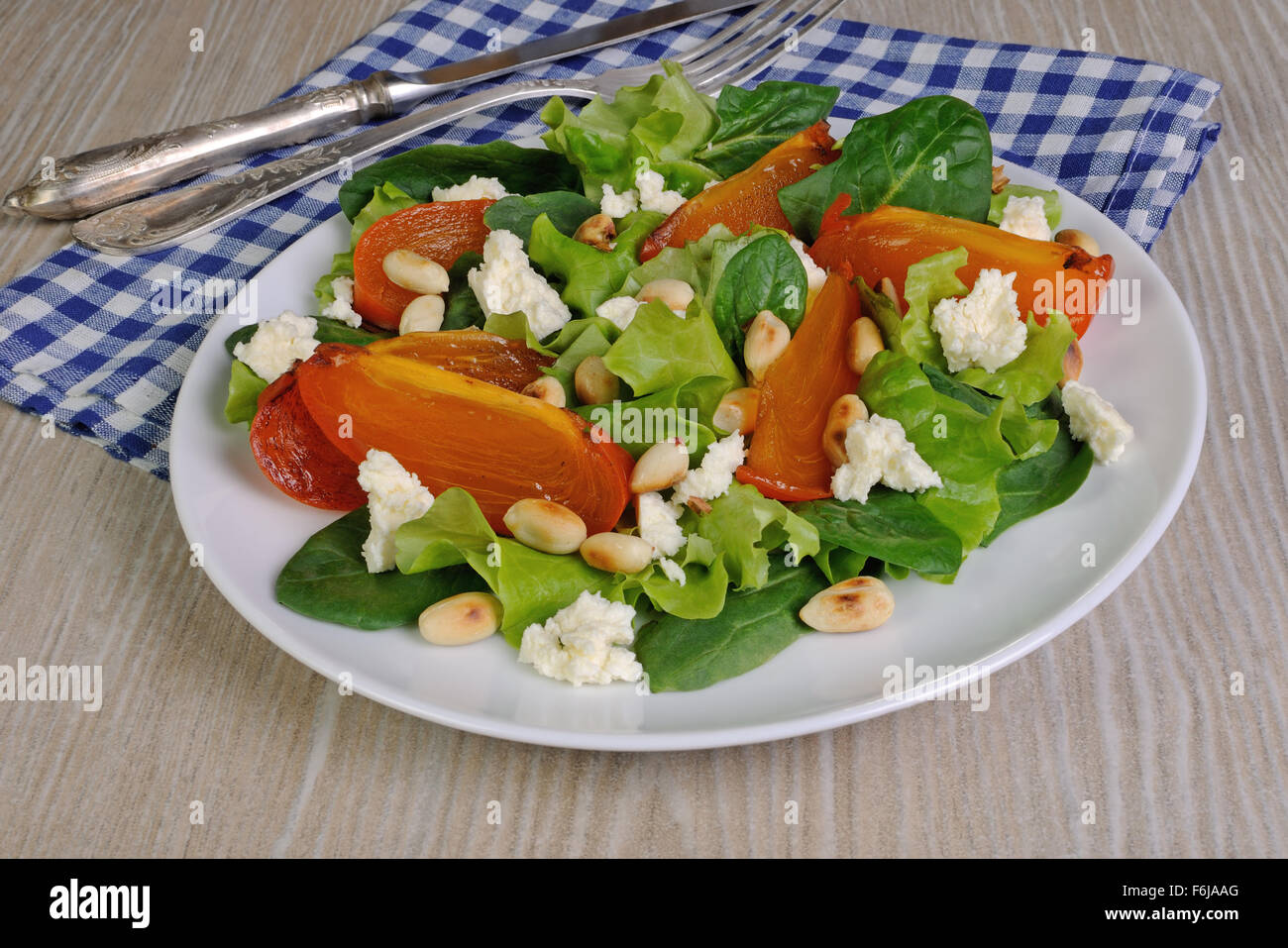 Frische Salat-Mix mit Kaki, Feta-Käse und Erdnüssen Stockfoto