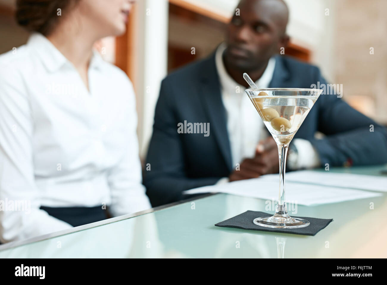 Schuss von Glas cocktail auf Theke mit zwei Geschäftsleute im Hintergrund diskutieren im Café sitzen hautnah. Stockfoto