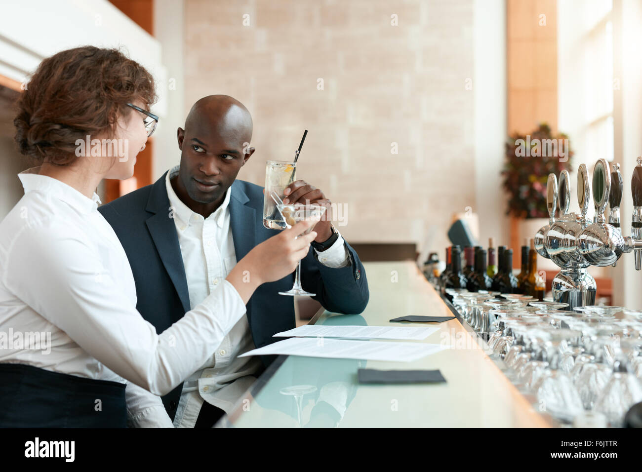Zwei junge Geschäftsleute Toasten Getränke im Café. Afrikanischen Geschäftsmann mit kaukasischen Partnerin ein Glas Getränk an Stockfoto
