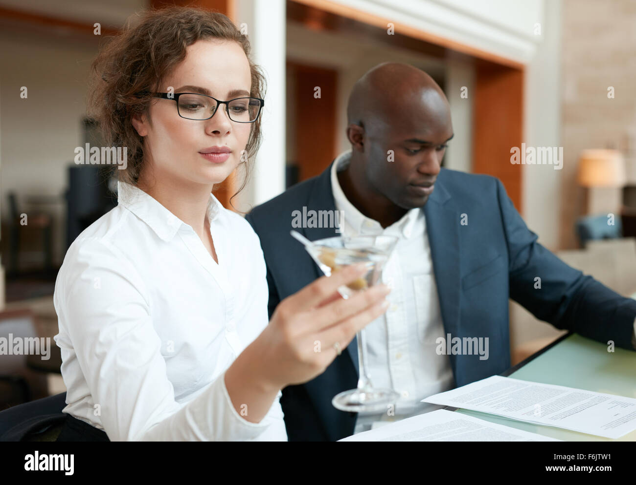 Schuss der Geschäftsfrau mit einem Glas cocktail mit ein Business-Mann sitzen am Tresen. Geschäftsleute, die im Café sitzen ein Stockfoto