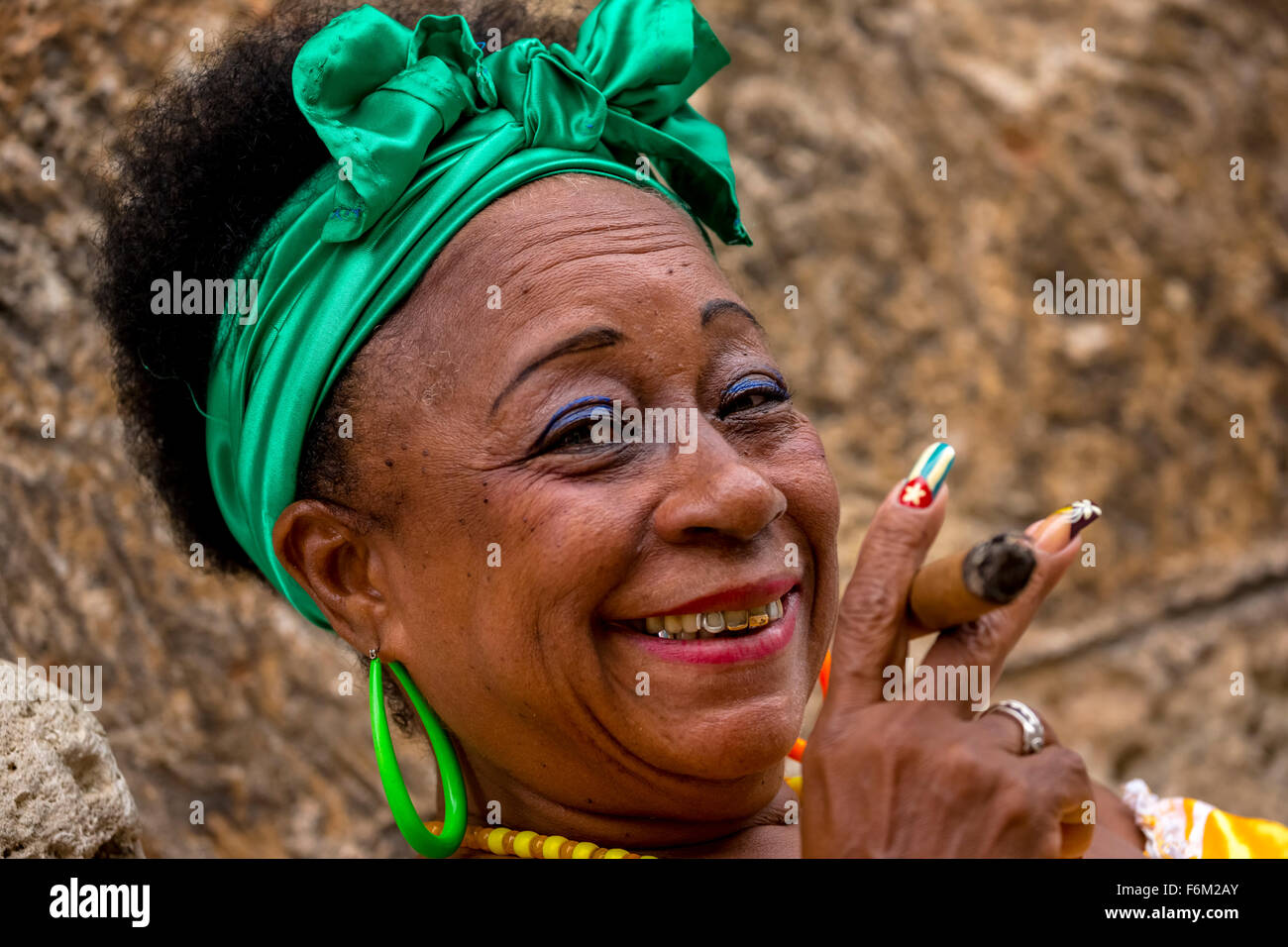alten machte stark kubanische Frau mit grünen Haaren beugen, Rauchen eine Havanna-Zigarre, kubanische Zigarre mit lackierten Fingernägeln mit kubanischen Flagge, Stockfoto