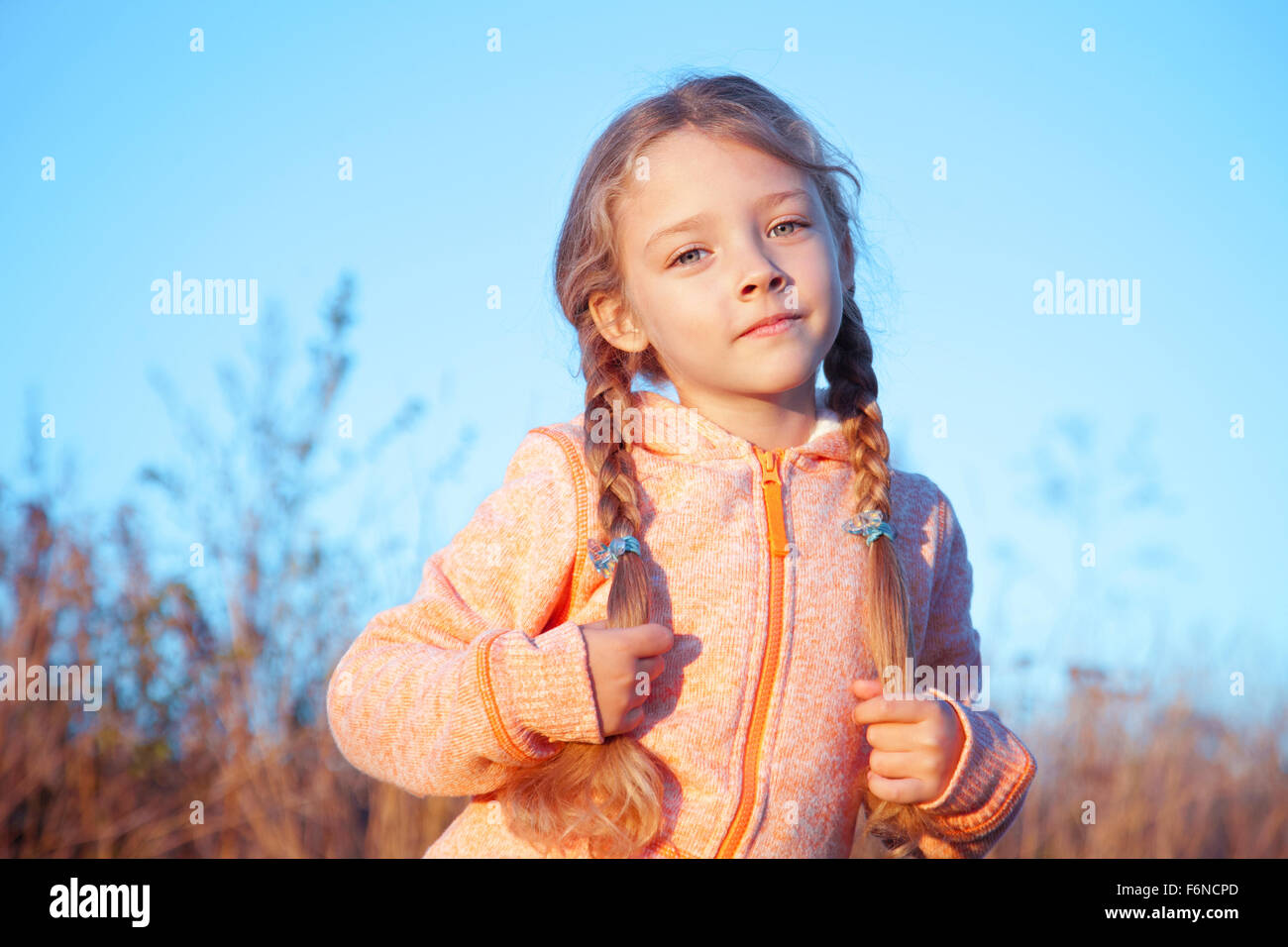 Porträt eines Mädchens mit Zöpfen an einem sonnigen Tag im freien Stockfoto