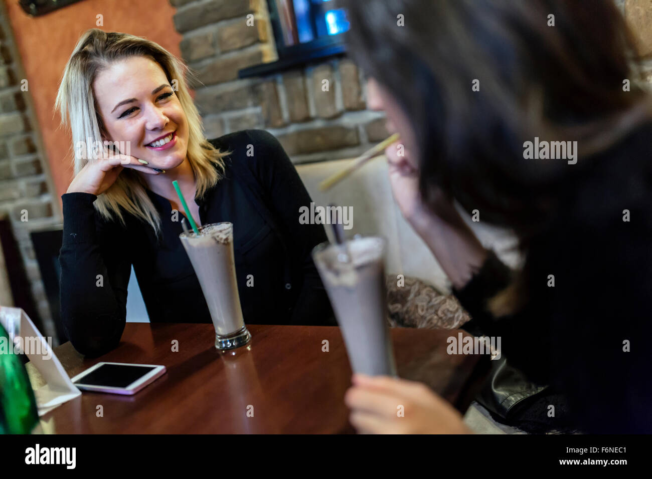 Zwei Frauen trinken und sprechen im Café und eine gute Zeit Stockfoto
