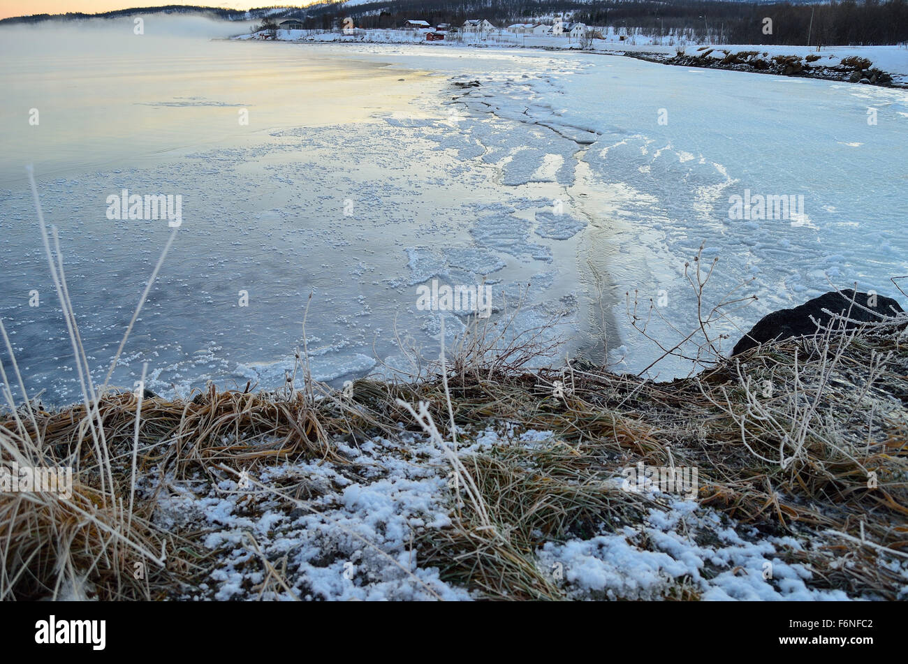 lange gefrorene Meeresufer mit dickem Eis und bunte Dämmerung Himmel und Nebel dichter Eisnebel Stockfoto