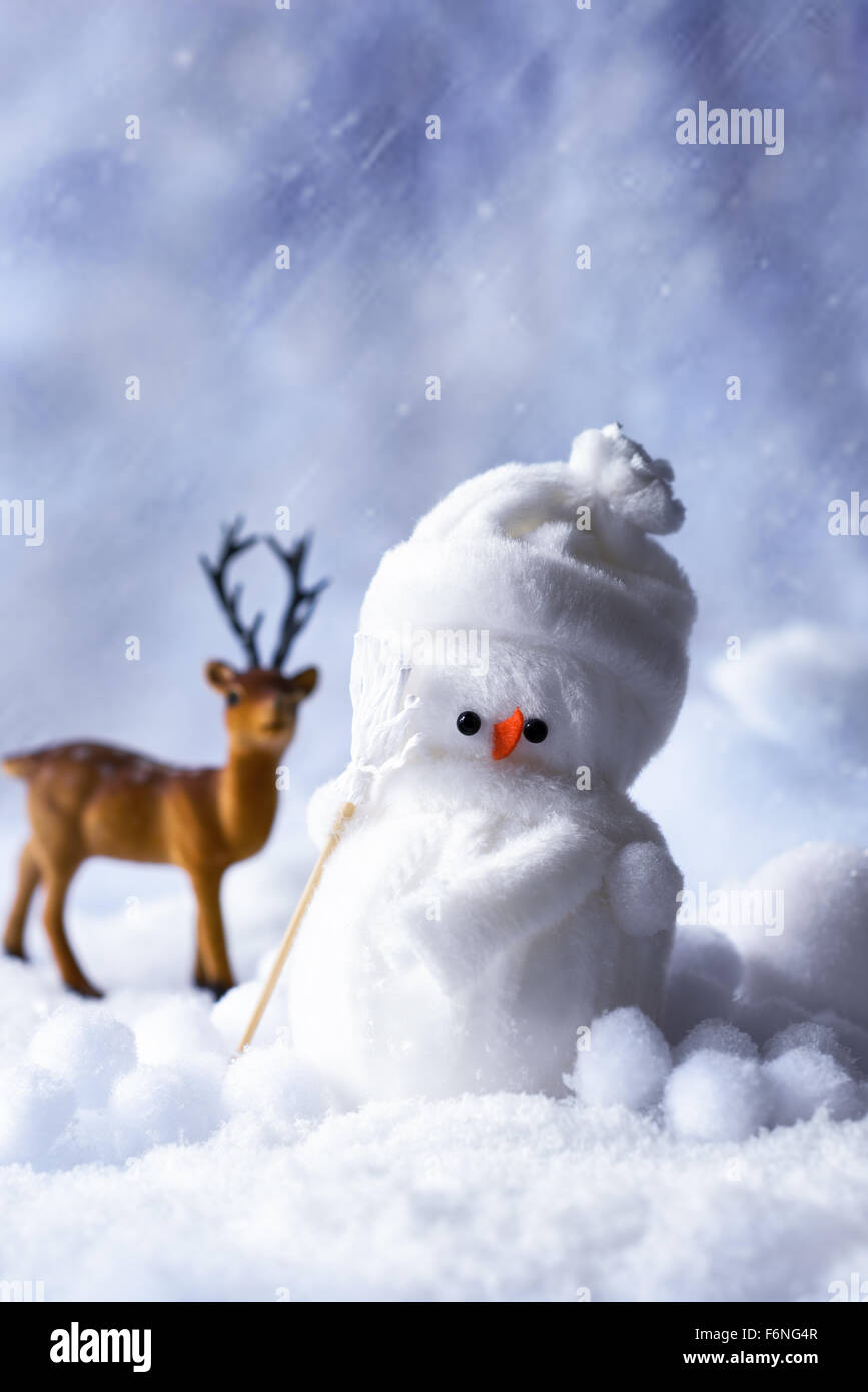 Schneemann Figur im Winter mit Rentier stehend im Hintergrund Stockfoto