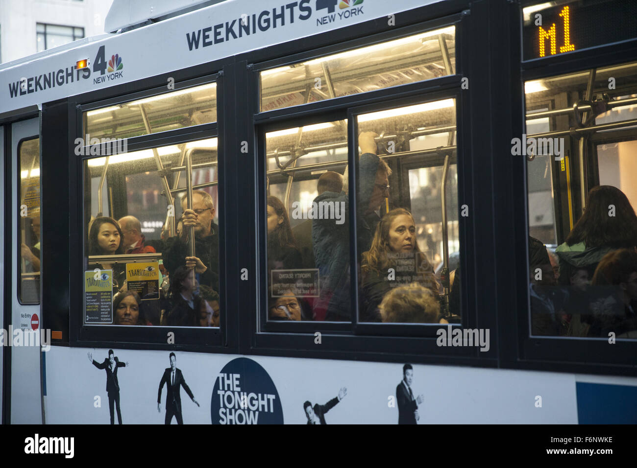 Menschen innerhalb eines Stadtbusses in Midtown Manhattan, NYC während der Rush Hour am Abend. Stockfoto