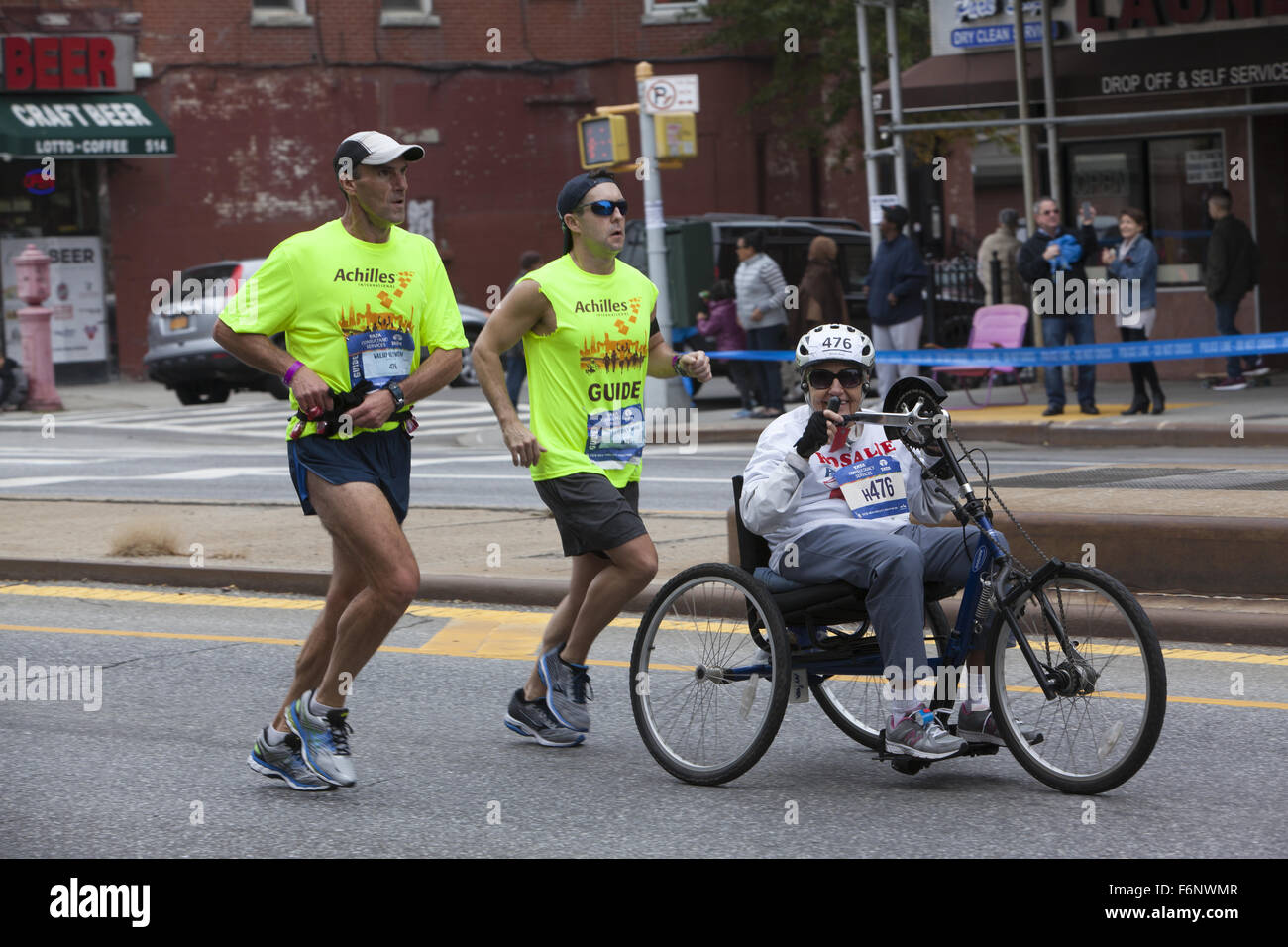 Läufer begleiten ältere behinderte Frau entlang 4th Avenue in Brooklyn entschlossen, das gesamte Verlauf der NYC-Marathon in die Pedale treten. Stockfoto