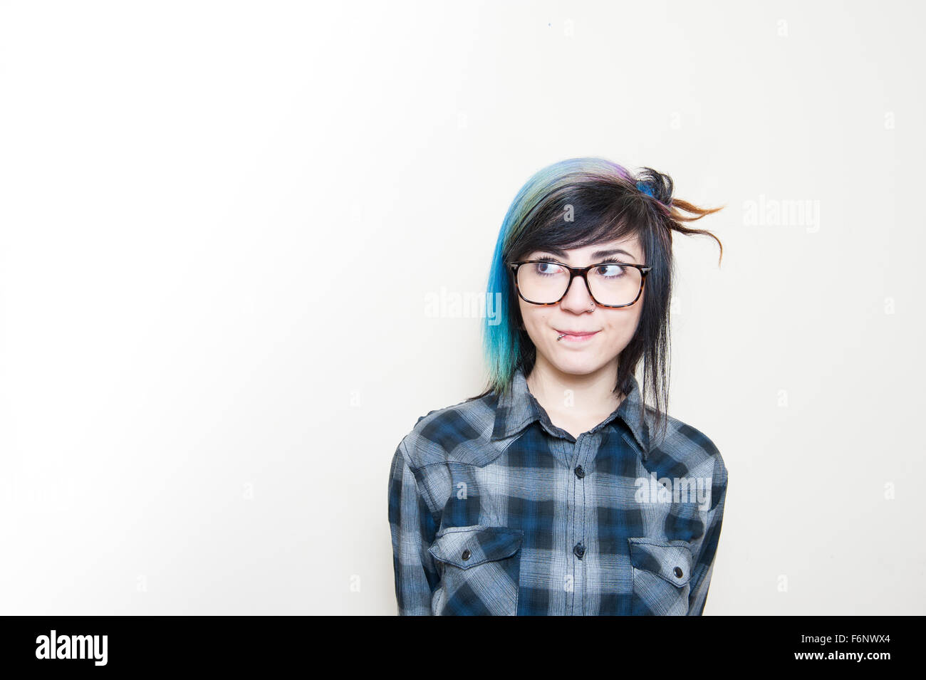 Lächelnde alternative Teen Frau im blauen Hemd Blick auf weißem Hintergrund Stockfoto