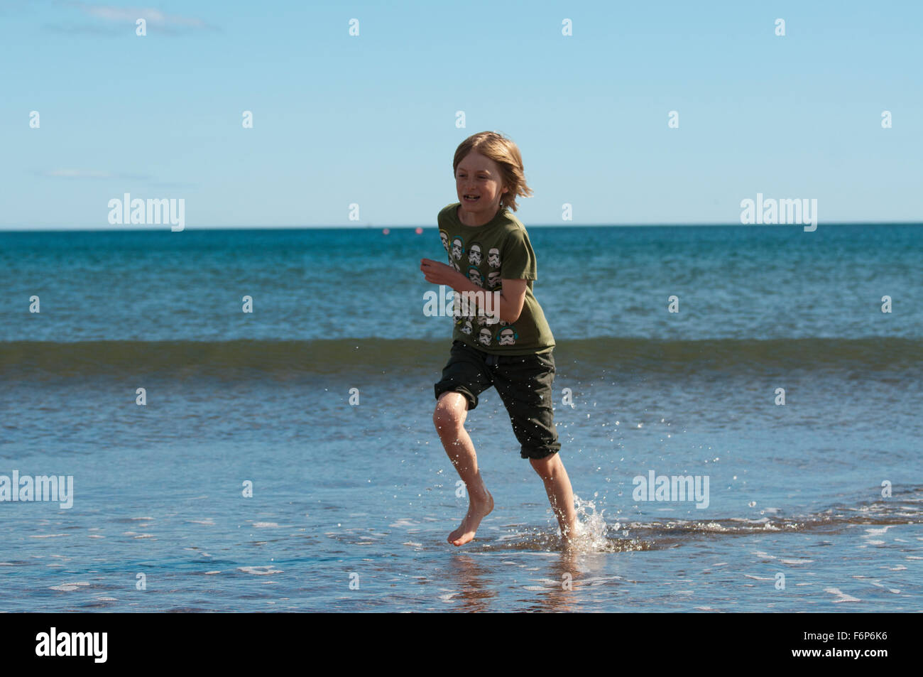 Junge im Meer laufen Stockfoto