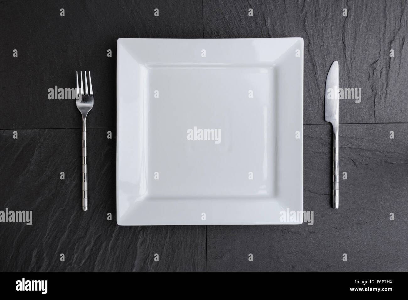 Draufsicht der weißen quadratischen Teller, Messer und Gabel. Stockfoto