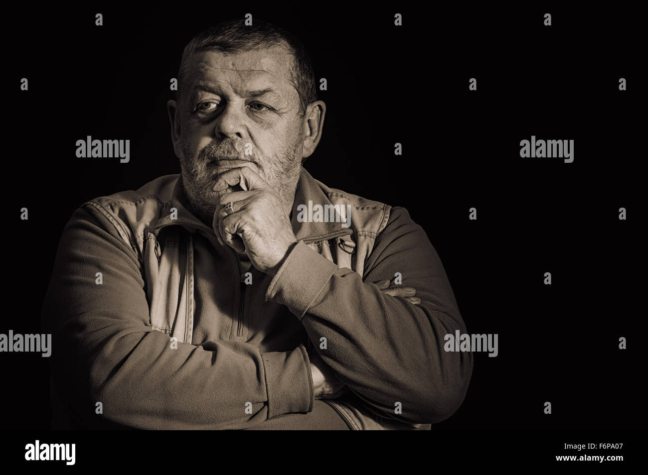 Schöne Sepia getönt Bild von einem nachdenklichen senior Mann vor einem dunklen Hintergrund Stockfoto