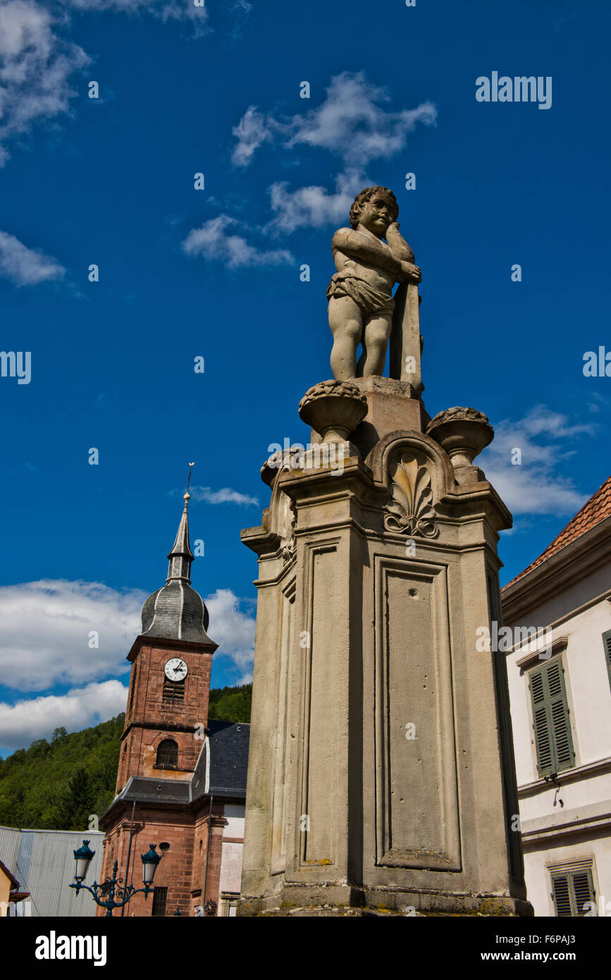 Eine steinerne Statue eines Cherub-Typs wird auf den Brunnen in der Mitte von Sainte-Marie-Aux-Mines Stockfoto