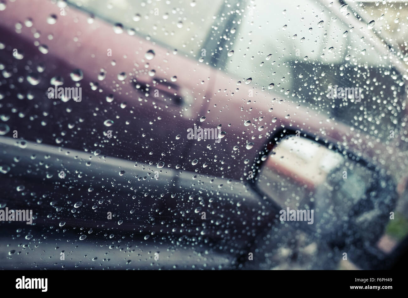 Nassen Sie Autofenster mit Regentropfen und einen Spiegel hinter. Nahaufnahme Foto mit Tiefenschärfe und flachen DOF, Vintage Tonwertkorrektur Stockfoto