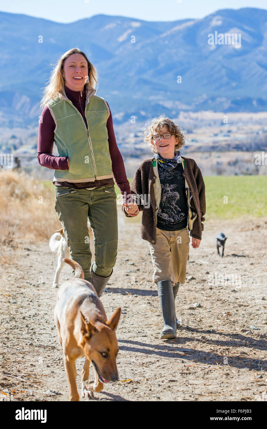 Attraktive Mutter; jungen Sohn und Hunde zu Fuß entlang Feldweg auf ranch Stockfoto