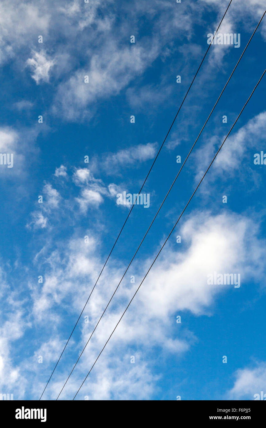 Ein Intensiv blauer Himmel mit weißen Wolken Puffy mit drei Mächte Zeilen halbiert die Aussendung elektromagnetischer Frequenzen Stockfoto