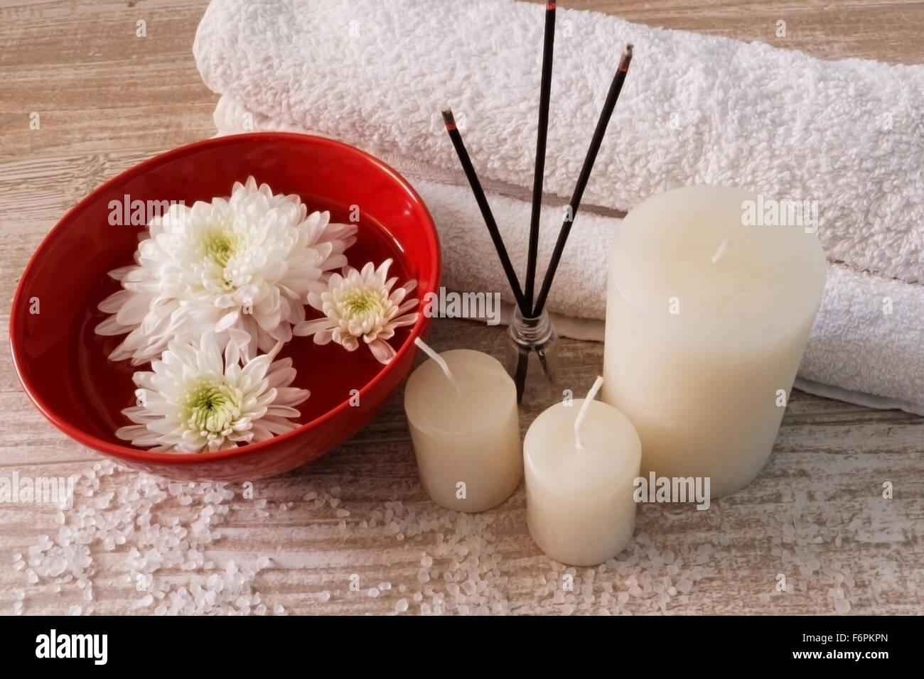 Spa-Komposition mit weißen Handtüchern, Kerzen, Blumen, Räucherstäbchen und Badesalz auf Holztisch Stockfoto