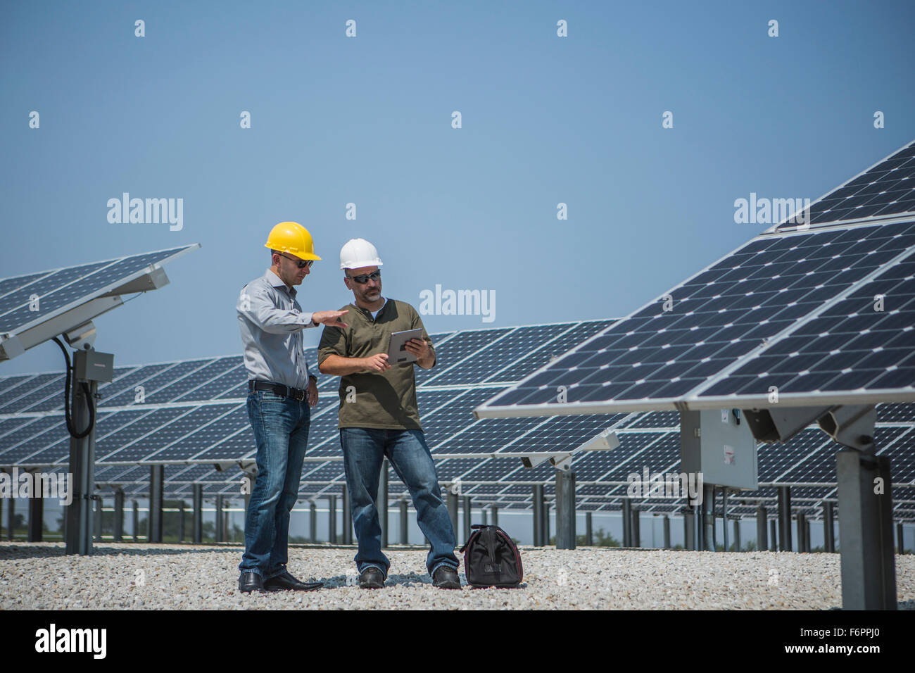 Kaukasische Techniker sprechen in der Nähe von Sonnenkollektoren Stockfoto