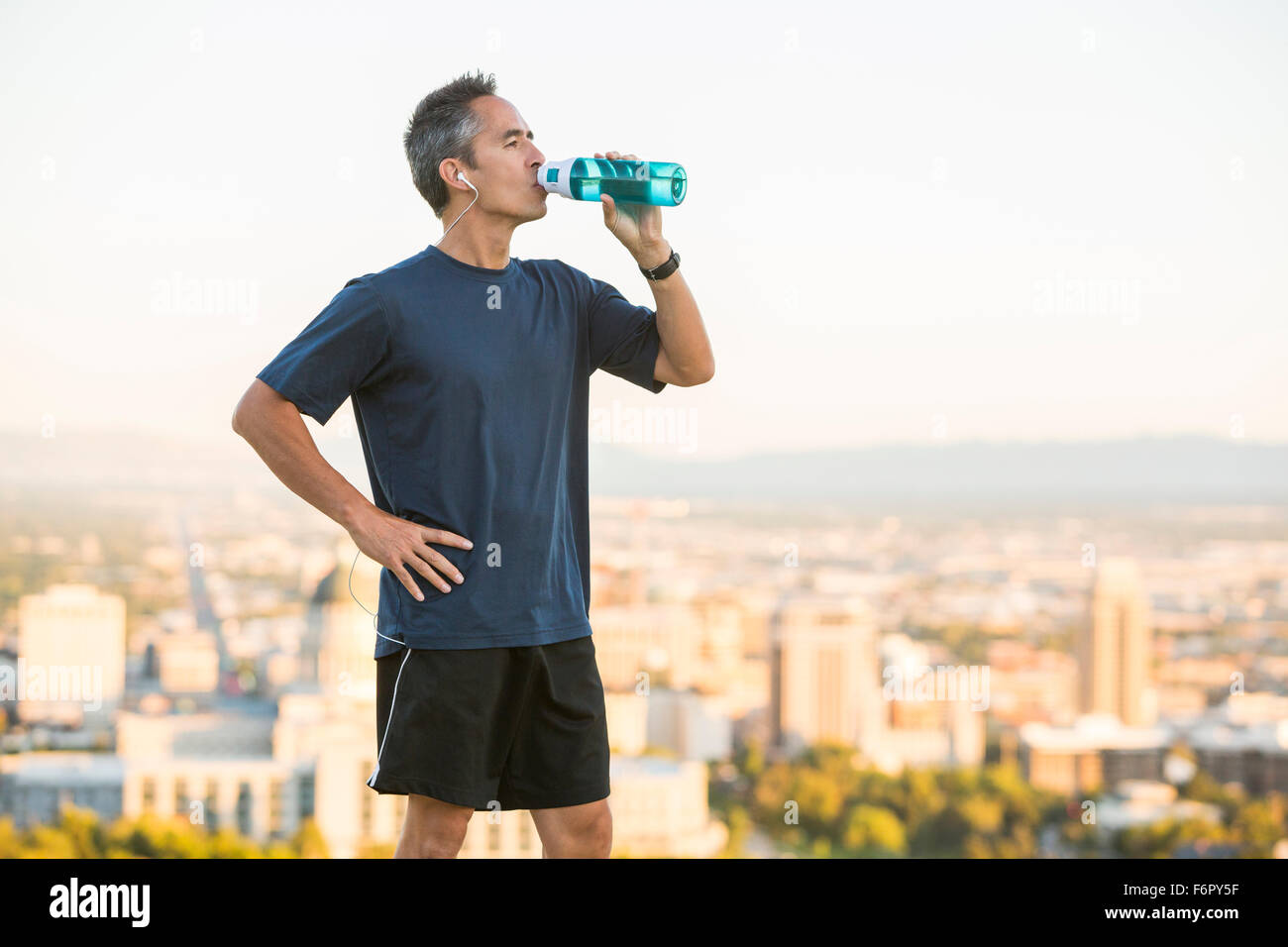 Gemischte Rassen Mann Trinkwasser Flasche auf städtischen Hügel Stockfoto